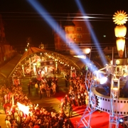 Vista de cima da entrada do festival de cinema de Gramado, com p&uacute;blico aglomerado em frente ao tapete vermelho. Um grande Kikito iluminado aparece em destaque no primeiro plano